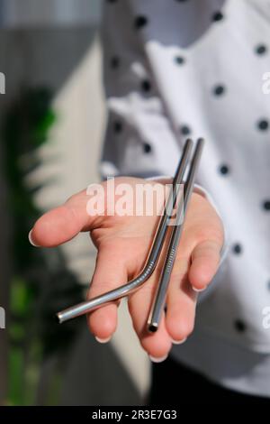 Frau mit wiederverwendbarem Metallstroh. Weibliche Hand auf wiederverwendbarem zusammenklappbarem Trinkhalm. Umweltfreundlicher Lifestyle und Konzept der Abfallvermeidung. Pl Stockfoto