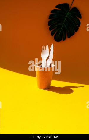 Holzgabeln und Pappbecher mit Platten auf farbigem Hintergrund. Umweltfreundliches Einweg-Geschirr. Verwendet in Fast Food, Restaurants, Stockfoto
