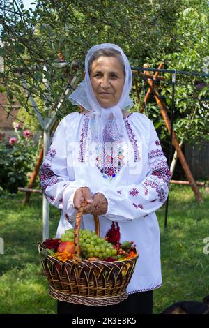 Eine Frau, die mit einem Obstkorb im Hof steht Stockfoto