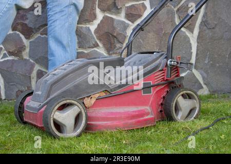 Der rote Mäher ist im Herbst alt auf dem grünen Gras Stockfoto