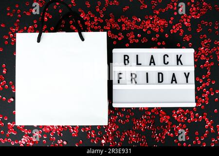 Lightbox mit schwarzem Text AM FREITAG auf dunklem Hintergrund mit Einkaufstaschen aus Papier, Verkaufskonzept. Vorlage Black friday Angebot m Stockfoto