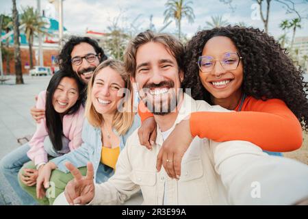 Eine Gruppe multirassischer Freunde, die lächeln und ein Selfie-Porträt machen. Junge Leute, die Spaß haben bei einem gesellschaftlichen Treffen. Ein fröhliches Team glücklicher Jugendlicher, die während eines Meetings mit einem Handy ein selbstfoto aufnehmen. Hochwertiges Foto Stockfoto
