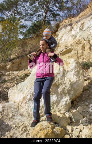 Ein glücklicher Mann mittleren Alters, der sein kleines Baby hält. Vater trägt ein Kind auf seiner Schulter Stockfoto