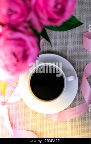 Tasse Kaffee und rosa Rosen. Urlaubskonzept, Rosenstrauß zum Geburtstag, Blumenstrauß zum Frühstück am Morgen. Stockfoto