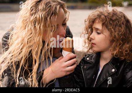 Die Mutter gibt ihrer Tochter Eis Stockfoto