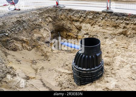 Installation eines neuen, modernen vertikalen Abwasserkanals aus schwarzem Kunststoff während des Austauschs unterirdischer Rohrleitungen auf der Stadtstraße Stockfoto