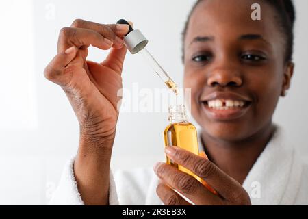 Flasche Serum mit Tropfen, der von der Pipette fällt Stockfoto