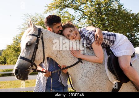 Das junge Paar hat Spaß mit Pferd Stockfoto