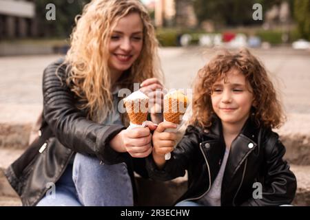 Die glückliche Mutter und Tochter halten beim Gehen Eis Stockfoto