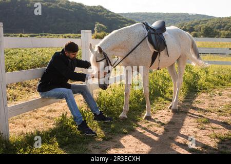 Der Mann ruht mit einem Pferd auf einer Ranch Stockfoto