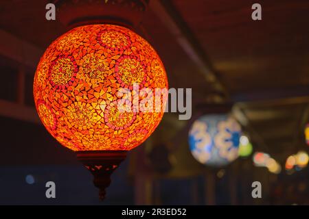 Leuchtend rote traditionelle, bunte türkische Lampe oder handgefertigte Laterne, selektiver Fokus auf Laterne, verschwommener Hintergrund, beliebte Souvenirlaternen im Café Stockfoto