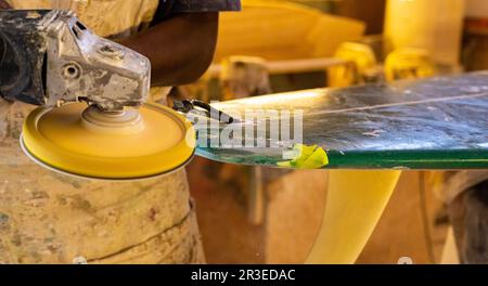 Ein afrikanischer Craftsman Surfboard Shaper, der in einer Reparaturwerkstatt arbeitet Stockfoto