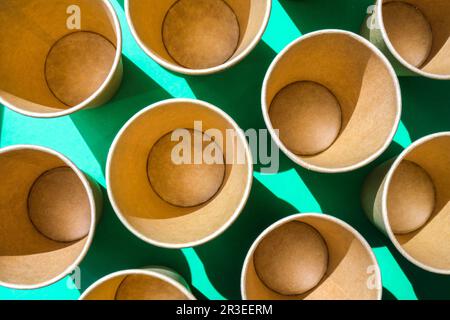 Leere recycelbare Pappbecher auf grünem Hintergrund. Viele Take-away-Becher zum Trinken. Umweltfreundlich. Zero Waste Kunststofffreies Konzept. Stockfoto