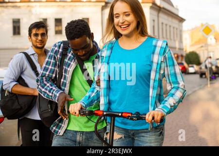 Das junge Paar hat Spaß beim Reiten Roller Stockfoto