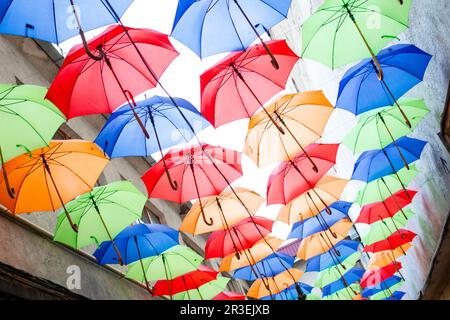 Die bunten Regenschirme oben auf der Straße in der Stadt Stockfoto