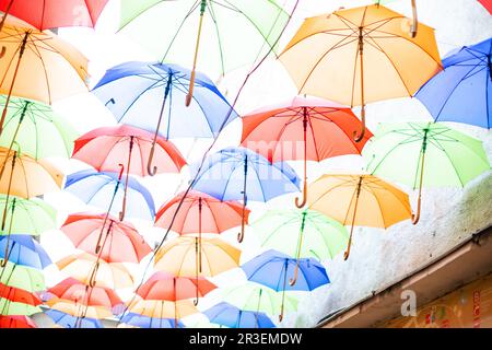 Die bunten Regenschirme oben auf der Straße in der Stadt Stockfoto