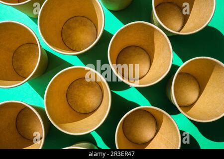 Leere recycelbare Pappbecher auf grünem Hintergrund. Viele Take-away-Becher zum Trinken. Umweltfreundlich. Zero Waste Kunststofffreies Konzept. Stockfoto