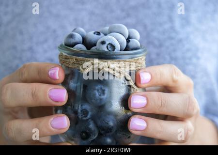 Eine Frau, die eine Schüssel mit gefrorenen Heidelbeeren hält. Erntekonzept. Weibliche Hände sammeln Beeren. Konzept der gesunden Ernährung. St Stockfoto