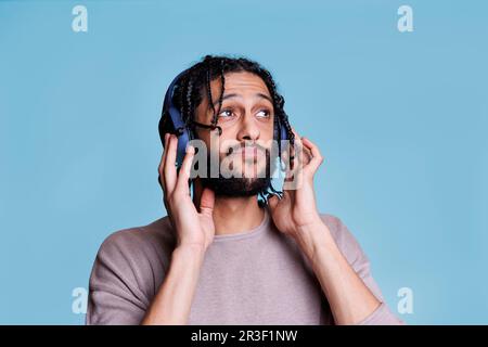 Junger Mann, der mit großen kabellosen Kopfhörern Musik hört Stockfoto