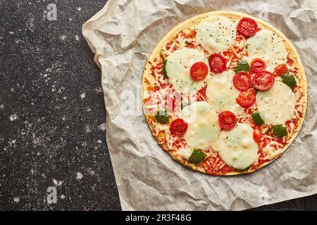 Fastfood gebackene Tiefkühlpizza mit Käse, Tomaten und Pesto. Bereit zum Essen. Stockfoto