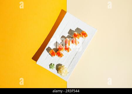 Sushi-Brötchen mit Aal, Garnelen, Gurke und Frischkäse, dekoriert mit rotem Kaviar. Hartes Licht, tiefer Schatten Stockfoto
