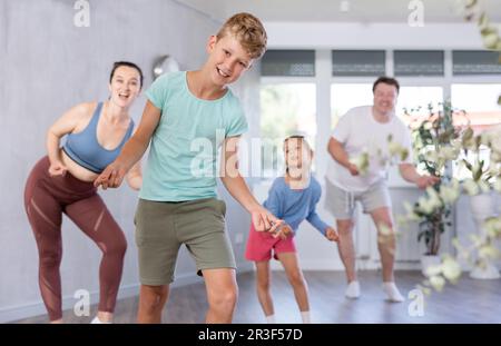 Glücklicher Junge, der mit seinen Familienmitgliedern Tanzbewegungen praktiziert Stockfoto