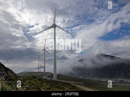 Mehrere Windturbinen sind in einer Bergregion vor dem Hintergrund dramatischer Himmel in Griechenland und Kreta aktiv Stockfoto