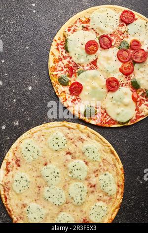 Fast Food, gebackene Tiefkühlpizza mit vier Käsesorten und Pizza mit Mozzarella-Käse, Tomaten und Pesto. Bereit zum Essen Stockfoto