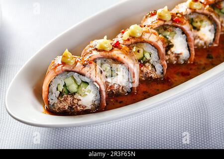 Gebackene warme Sushi-Brötchen mit Aal, Gurke und geräuchertem Lachs Stockfoto
