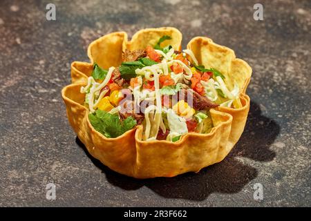 Taco-Salat in Tortilla-Schüssel mit Rind, Käse, Mais und Salat Stockfoto