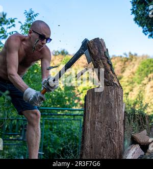 Junger Mann, der Holz spaltet Stockfoto