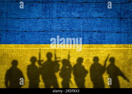 Konzeptionelles Bild eines Krieges zwischen Russland und der Ukraine mit Schatten eines Soldaten gegen Mauer mit Flaggen Stockfoto