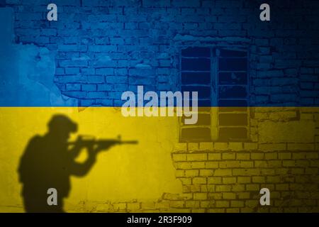 Konzeptionelles Bild eines Krieges zwischen Russland und der Ukraine mit Schatten eines Soldaten gegen Mauer mit Flaggen Stockfoto
