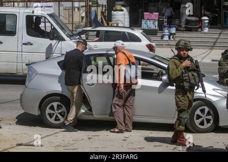 Nablus, Palästina. 23. Mai 2023. Israelische Soldaten und Sanitäter inspizieren das Auto eines israelischen Siedlers, nachdem es im besetzten Westjordanland in der Stadt Hawara südlich von Nablus mit Steinen besetzt wurde. Zwei israelische Siedler wurden verletzt, nachdem palästinensische Jugendliche in der Stadt Hawara Steine nach ihrem Auto warfen, während sie vorbeifuhren. Kredit: SOPA Images Limited/Alamy Live News Stockfoto