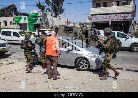 Nablus, Palästina. 23. Mai 2023. Israelische Soldaten und Sanitäter inspizieren das Auto eines israelischen Siedlers, nachdem es im besetzten Westjordanland in der Stadt Hawara südlich von Nablus mit Steinen besetzt wurde. Zwei israelische Siedler wurden verletzt, nachdem palästinensische Jugendliche in der Stadt Hawara Steine nach ihrem Auto warfen, während sie vorbeifuhren. Kredit: SOPA Images Limited/Alamy Live News Stockfoto