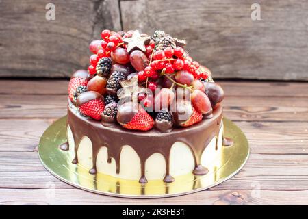 Köstlicher Käsekuchen mit frischen Erdbeeren, Himbeeren, Heidelbeeren, Johannisbeeren und Trauben auf Holzhintergrund, Freier Platz für Ihren Text. Stockfoto