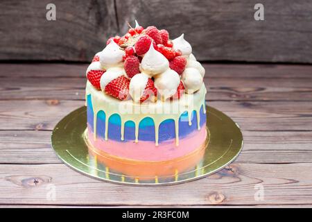Rosafarbener, violetter und blauer Kuchen mit geschmolzener weißer Schokolade, frischen Erdbeeren in Schokolade getaucht, Himbeeren, roter Johannisbeere und Baiser Stockfoto