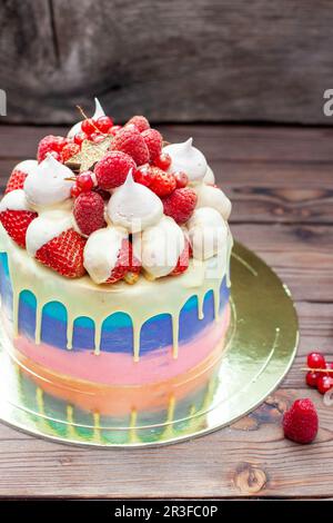 Rosafarbener, violetter und blauer Kuchen mit geschmolzener weißer Schokolade, frischen Erdbeeren in Schokolade getaucht, Himbeeren, roter Johannisbeere und Baiser Stockfoto