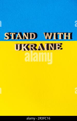 Ukrainische Staatsflagge aus Papier. STEH MIT DEM TEXT UKRAINE AUF. Stoppt Den Krieg. Das Konzept, den Krieg in der Ukraine zu beenden. Nationales Sym Stockfoto