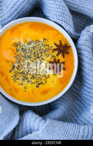 Hausgemachte Karotten, Ingwer, Curcuma, scharfe Suppe. Traditionelle Kürbissuppe der Saison mit cremiger seidiger Textur im gemütlichen Pullover Stockfoto