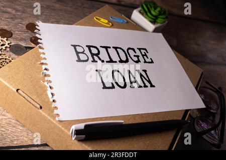 Geschäftskonzept. Text Bridge Loan Schreiben auf Papier und Stift, Brillen und Dokumenten Stockfoto