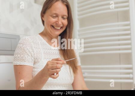 Frau mittleren Alters mit Schwangerschaftstest auf der Toilette Stockfoto