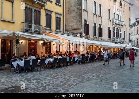 Touristen essen in einer Pizzeria auf Asphalt in Rio Terà Farsetti bei Sonnenuntergang, Sestiere von Cannaregio, Venedig, Veneto, Italien Stockfoto