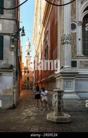 Calle (enge Gasse) neben der Scuola Grande di San Rocco (rechts) mit dem Glockenturm der Kirche San Pantalon im Hintergrund, Venedig, Italien Stockfoto