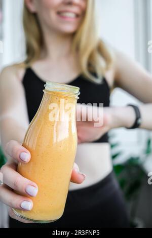 Junge, blonde Frau, die vegane Smoothies trinkt, trinkt Entgiftung. Frau, die zu Hause Yoga macht. Saubere Ernährung, Gewichtsverlust, Stockfoto