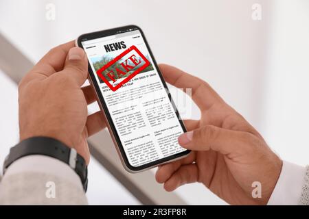 Gefälschte Informationen. Ein Mann, der zu Hause Nachrichten mit dem Handy liest, Nahaufnahme Stockfoto