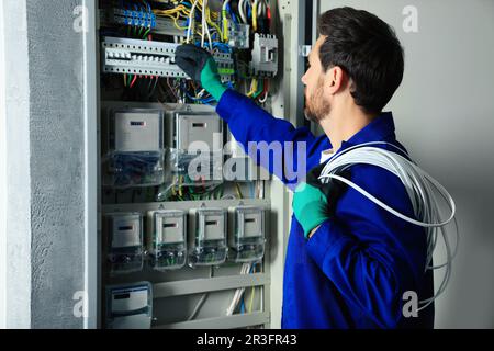 Elektriker mit Leitungen, die die Leistungsschalter im Sicherungskasten in Innenräumen ausschalten Stockfoto