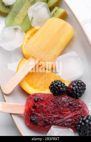 Köstliches Eis am Stiel, Eiswürfel und frisches Obst auf dem Teller, Nahaufnahme Stockfoto