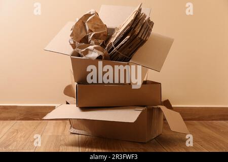 Altpapierhaufen auf Holzboden in der Nähe beiger Wände Stockfoto