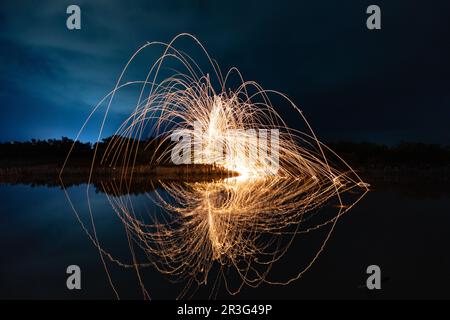 Wunderschöne Figuren und Lichtblitze, die sich nachts in einem See spiegeln. Stockfoto